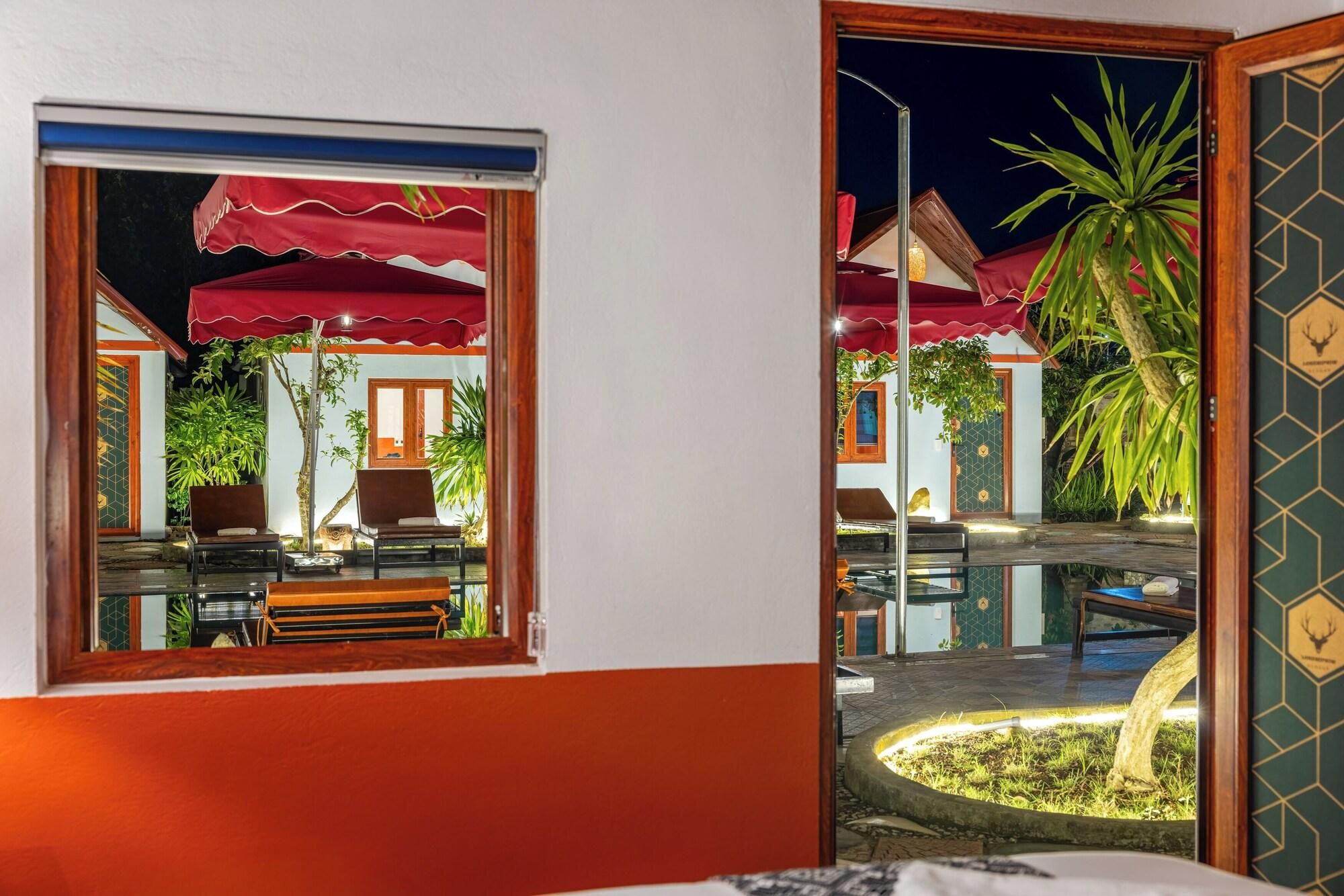 A hotel room with a view of an outdoor pool area, a red umbrella, and a wooden chair.
