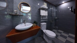 Une salle de bain moderne avec un meuble-lavabo en bois, un lavabo blanc, des toilettes et une douche séparée par une paroi de verre.
