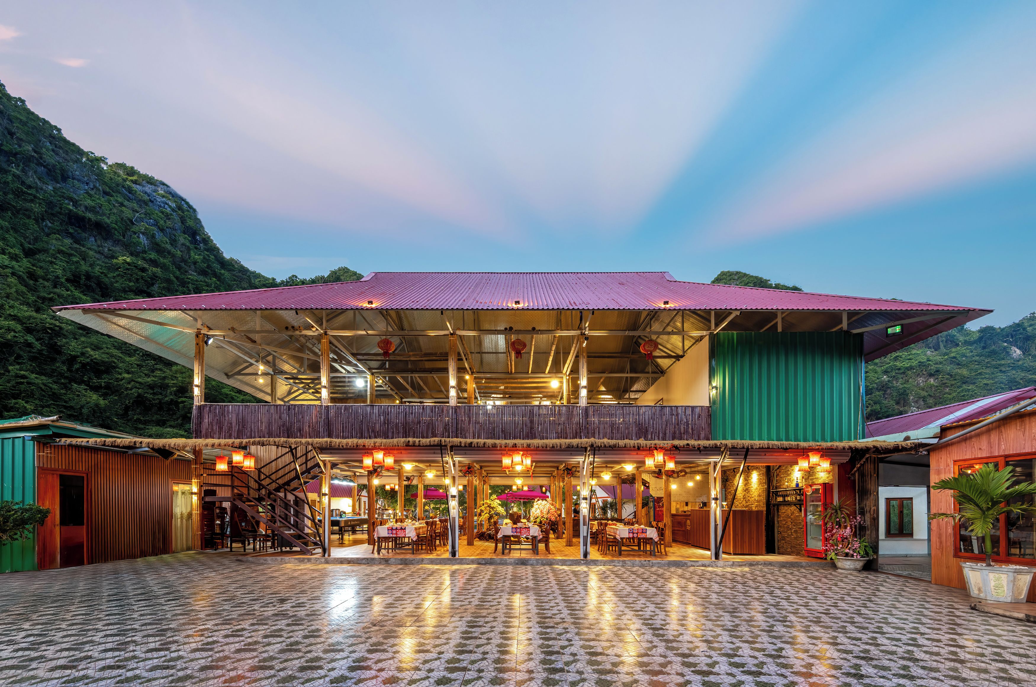 A restaurant with a covered outdoor seating area, a staircase, and a view of the surrounding greenery.