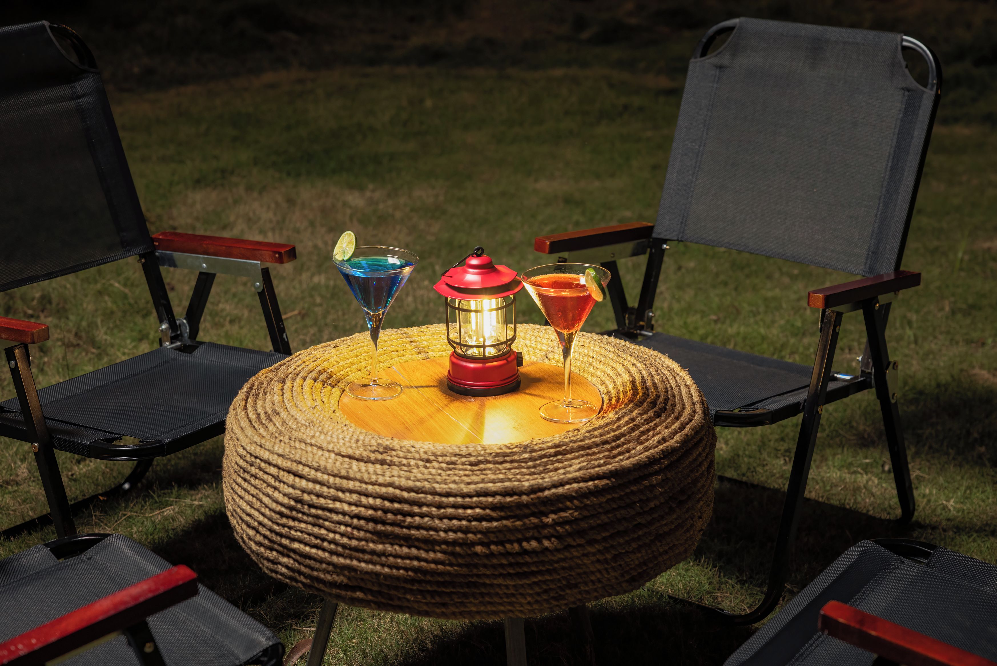 A round table with a woven base surrounded by four chairs with metal frames and dark fabric seats.