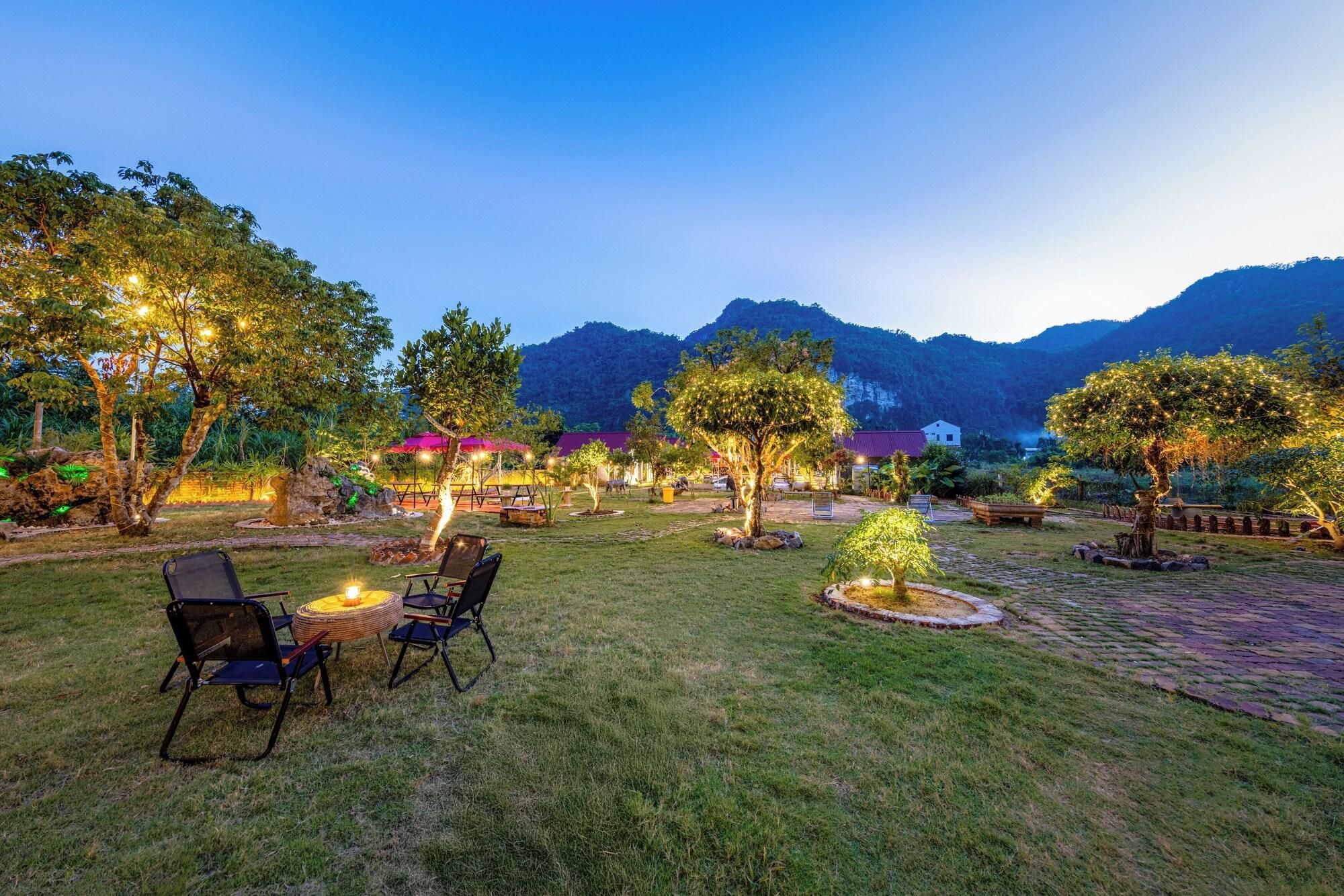 A well-maintained outdoor area with seating arrangements and trees, surrounded by mountains.