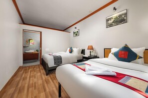 Habitación de hotel con dos camas, suelo de madera, baño con espejo y un cuadro en la pared.