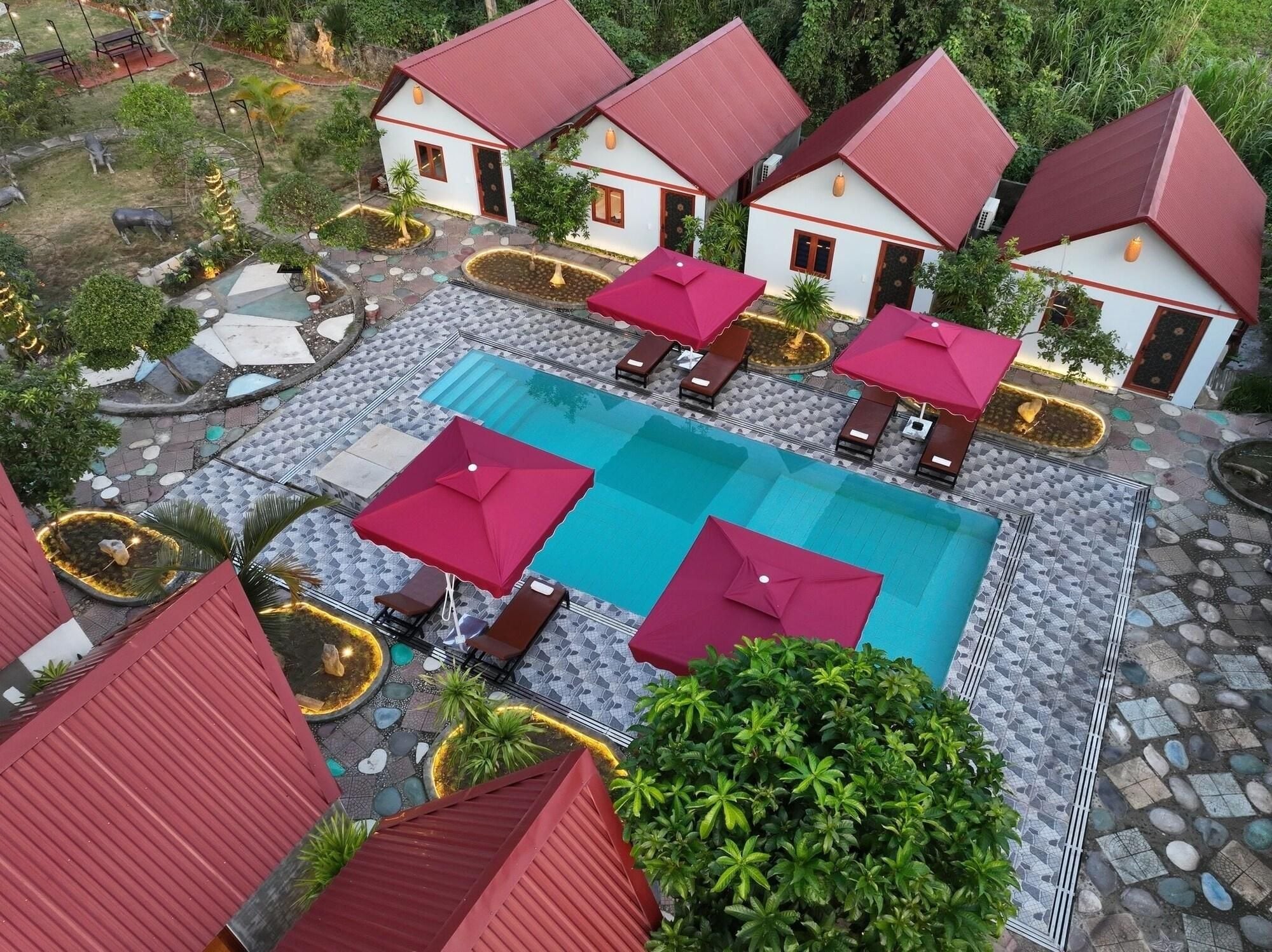 A pool area with multiple lounge chairs and umbrellas, surrounded by white buildings with red roofs.