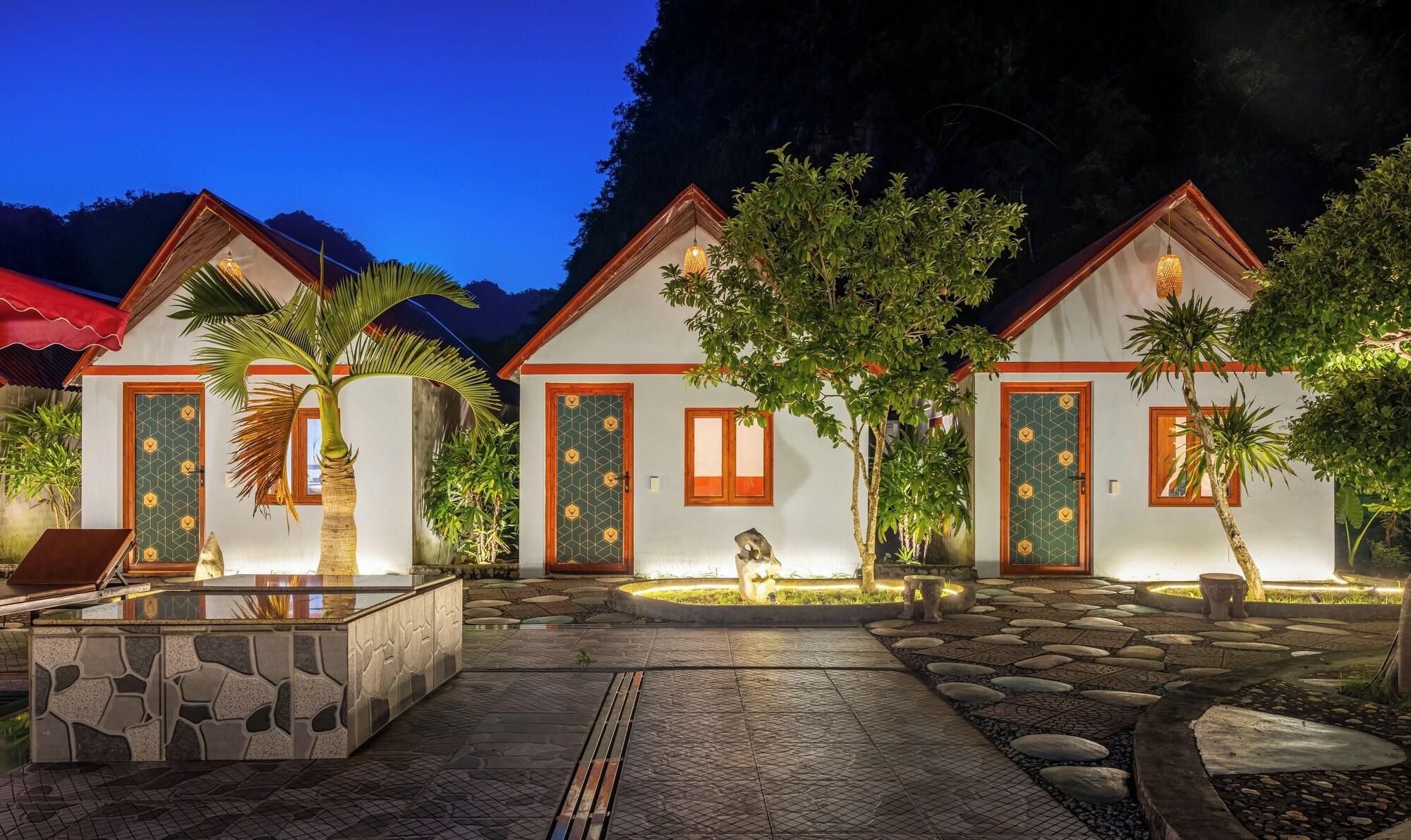 A resort with three villas, each with a tiled entrance, a small garden, and a stone pathway leading to a pool area.
