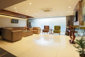 A spacious lobby with a sofa set, armchairs, a small table, and a decorative plant. - Hotel Sakura By Maps, Huda City Center (Gurugram)
