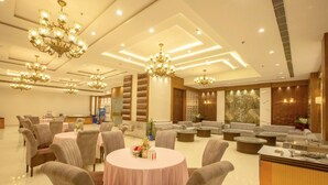 A spacious hotel lobby with multiple seating areas, including round tables and sofas, and a reception desk. - Hotel Sakura By Maps, Huda City Center (Gurugram)