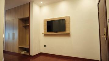 A room with a wooden wardrobe, a mounted TV, and a door.