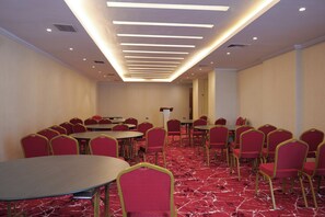 A conference room with round tables and red chairs, a red carpeted floor, and a modern ceiling with recessed lighting. - Crescent International Hotel Bole (Addis Ababa)