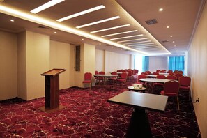 A conference room with a red carpet, multiple tables, and red chairs. - Crescent International Hotel Bole (Addis Ababa)