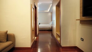 A hallway with wooden flooring, a bed in the background, and a TV mounted on the wall. - Crescent International Hotel Bole (Addis Ababa)