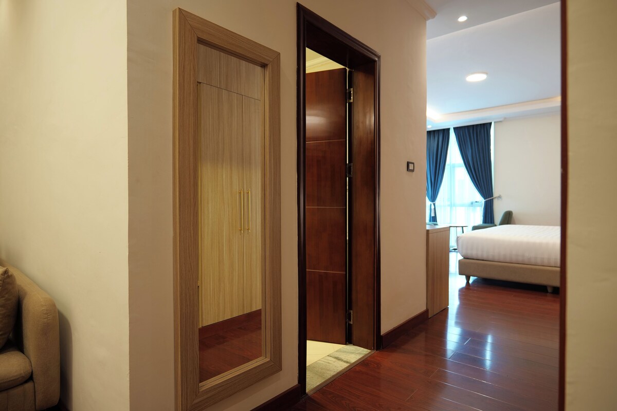 A hotel room with a wooden wardrobe, a bed, and a small desk.