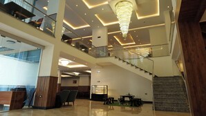 A multi-level hotel lobby with a grand chandelier, a staircase, and a reception desk. - Crescent International Hotel Bole (Addis Ababa)