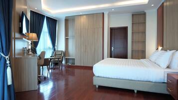 A modern hotel room with a large bed, a desk with a chair, a wardrobe, and a TV mounted on the wall.