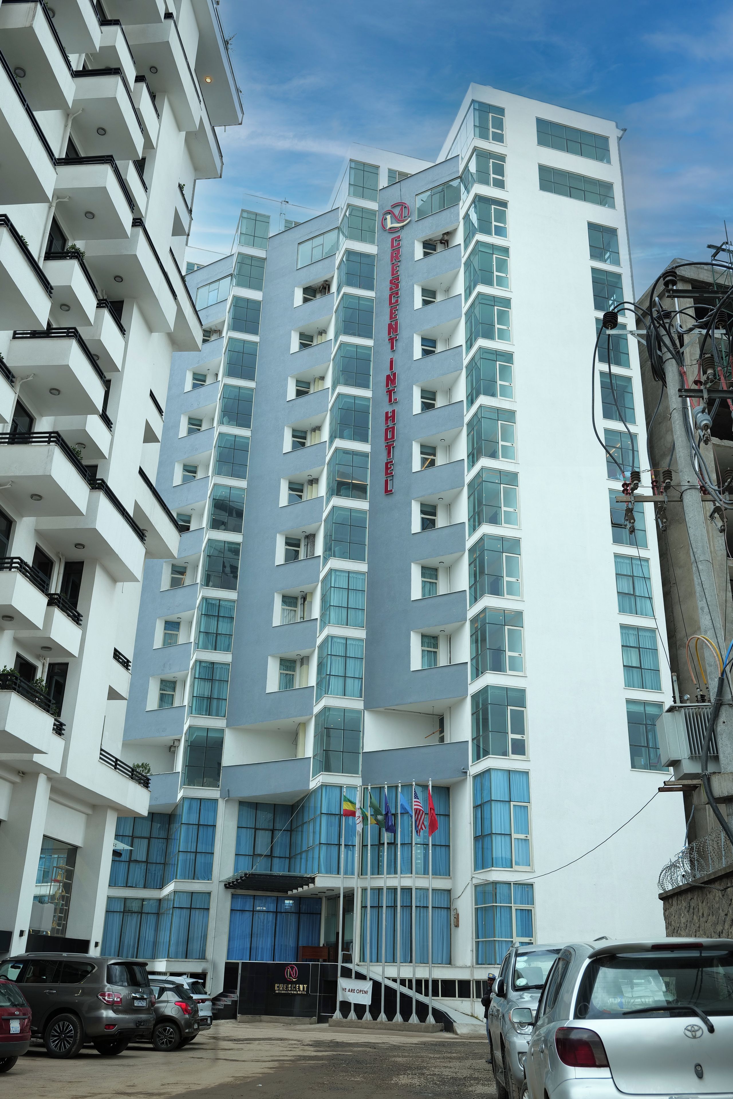 A multi-story hotel with a prominent sign, balconies, and a parking area.