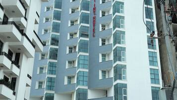 A multi-story hotel with a prominent sign, balconies, and a parking area.