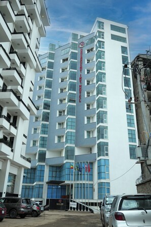 A multi-story hotel with a prominent sign, balconies, and a parking area. - Crescent International Hotel Bole (Addis Ababa)