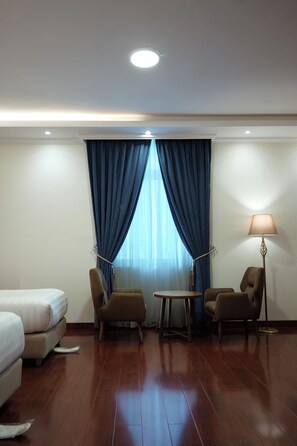 A hotel room with a bed, two armchairs, a small table, and a floor lamp. - Crescent International Hotel Bole (Addis Ababa)