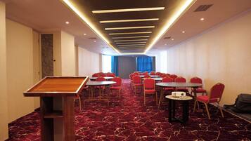 A conference room with a red carpet, round tables, and red chairs.