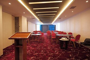 A conference room with a red carpet, round tables, and red chairs. - Crescent International Hotel Bole (Addis Ababa)