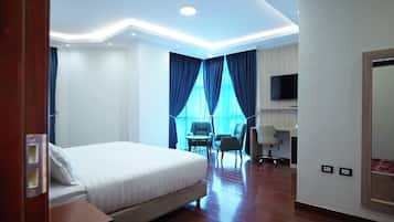 A hotel room with a large bed, a desk, a chair, and a TV.