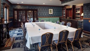 A conference room with a long table, chairs, and a green upholstered bench. - Irish Cottege Inn & Suites (Galena)