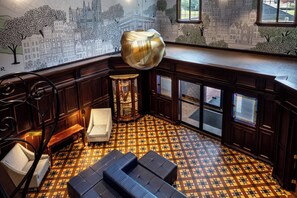 A room with a checkered floor, a large hanging light fixture, and a mural of a cityscape on the wall. - Irish Cottege Inn & Suites (Galena)