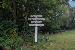 Un poste de madera con flechas direccionales y texto que indica senderos para caminatas.