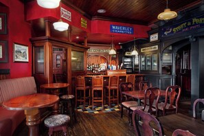 A bar area with wooden furniture, a bar counter, and various signs including one for Waverley Cigarettes. - Irish Cottege Inn & Suites (Galena)