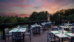 An outdoor dining area with tables and chairs, surrounded by a wooden deck and a railing. - Irish Cottege Inn & Suites (Galena)
