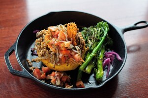 Una sartén con un plato que incluye granos, verduras y un trozo de carne.
