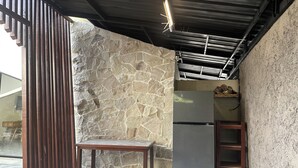 Una cocina con pared de piedra, un refrigerador y una mesa de madera.