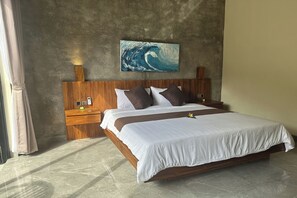 A large bed with a wooden headboard, white bedding, and a single flower decoration. There is a wooden nightstand with a lamp and a small picture frame. A large painting of a wave is on the wall above the bed. - Nawan Nusa Dua Bali By Zuzu (Kutuh)