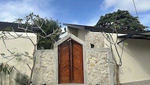 Una casa con un gran puerta de madera, muros de piedra y techo de tejas.