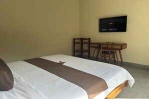 Une chambre d’hôtel avec un lit, un bureau et un téléviseur fixé au mur.