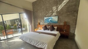 A modern bedroom with a large bed, a wooden headboard, a nightstand, and a painting of a wave. - Nawan Nusa Dua Bali By Zuzu (Kutuh)