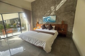 A modern bedroom with a large bed, a wooden headboard, a nightstand, and a painting of a wave. - Nawan Nusa Dua Bali By Zuzu (Kutuh)