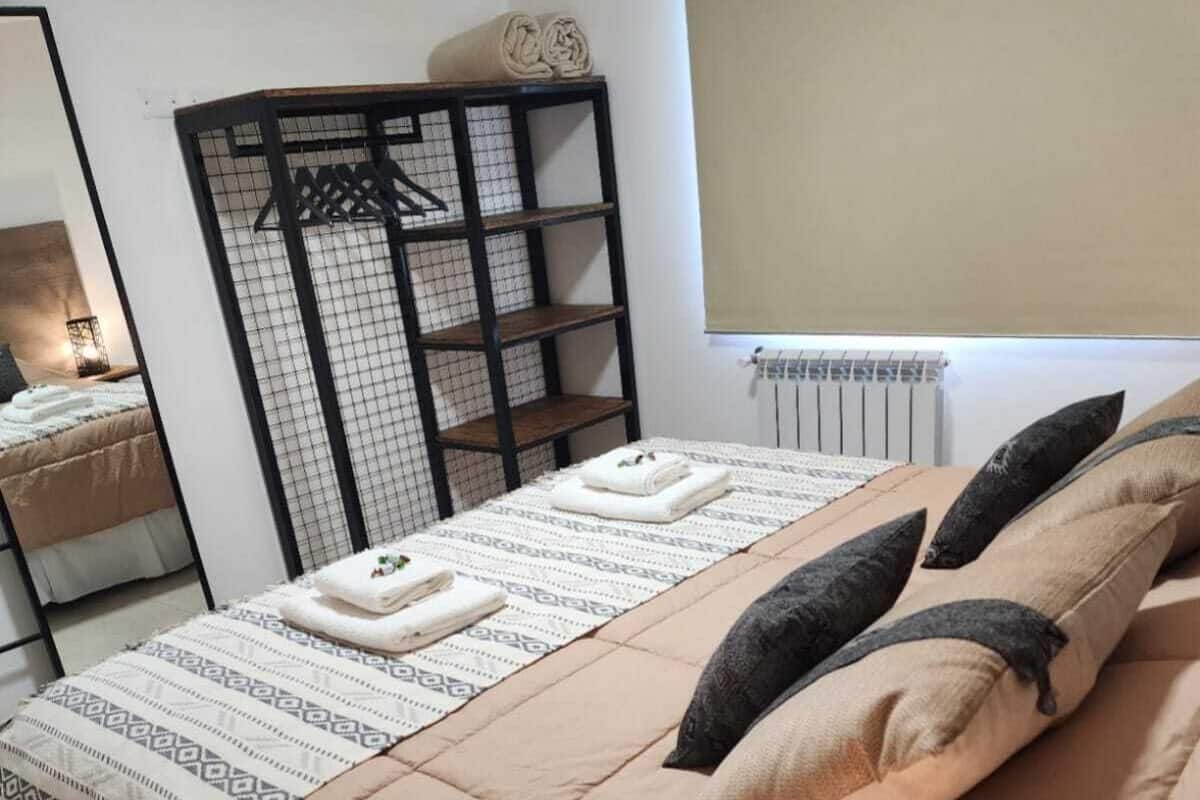 A bedroom with a bed, a window, a radiator, and a mirror.