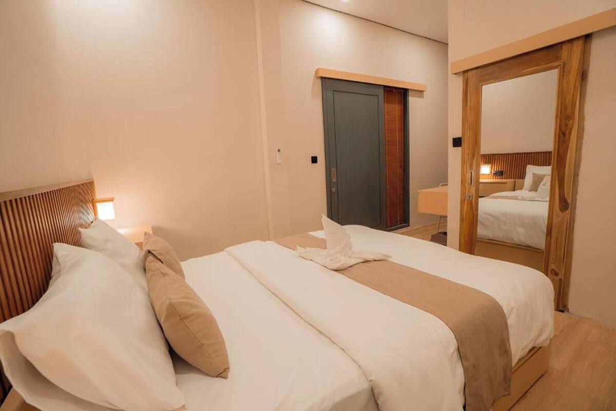 Een hotelkamer met een groot bed, een houten hoofdbord, een kledingkast en een spiegel.