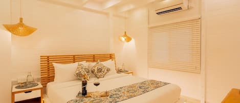 Un dormitorio con cabecera de madera, cama con colcha floral, mesitas de noche con lámparas y un ventilador de techo.