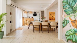 A modern kitchen with white cabinets, a central island, and pendant lighting. - Elivaas House Of Neptune (Morjim)