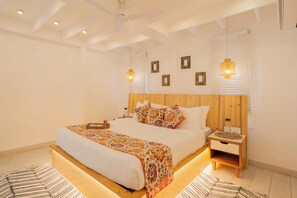 A spacious bedroom with a large bed, wooden headboard, bedside tables, and decorative wall sconces. - Elivaas House Of Neptune (Morjim)