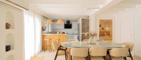 Una cocina moderna con armarios blancos, una isla central e iluminación colgante.