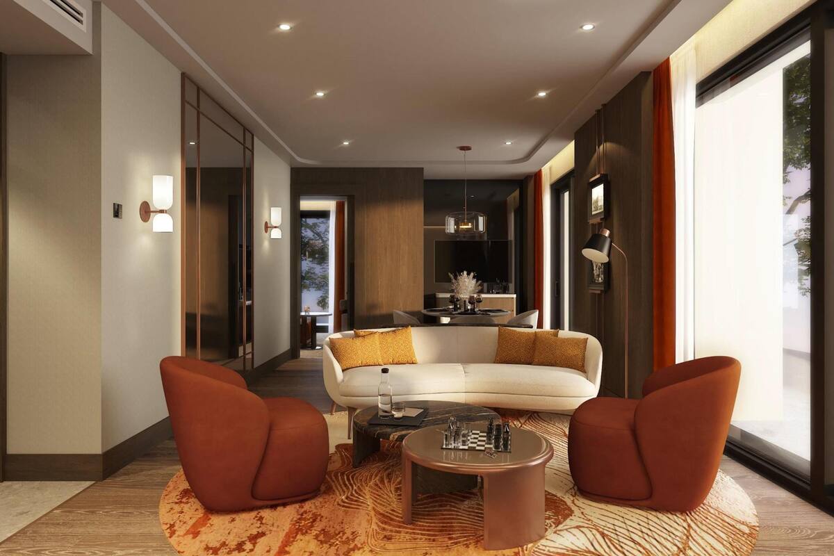 A modern living room with a white sofa, two red armchairs, a coffee table, and a patterned rug.