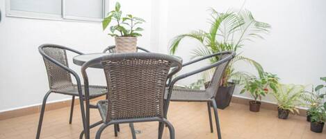 A room with a tiled floor, a round table with chairs, and several potted plants.
