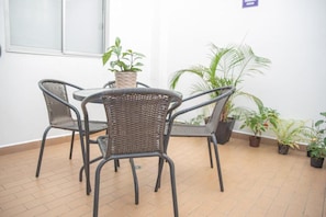 Una habitación con piso de baldosas, una mesa redonda con sillas y varias plantas en macetas.