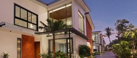 Uma casa moderna de dois andares, com janelas amplas, telhado plano e entrada com calçada.