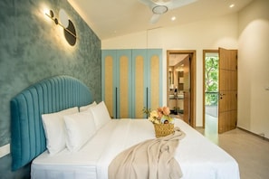 A bedroom with a bed, a wall-mounted light fixture, and a door leading to a balcony. - Elivaas Cloud 7-luxury Villa In Goa (Vagator)
