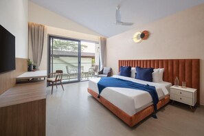A hotel room with a bed, bedside table, and a desk with chairs. - Elivaas Cloud 7-luxury Villa In Goa (Vagator)