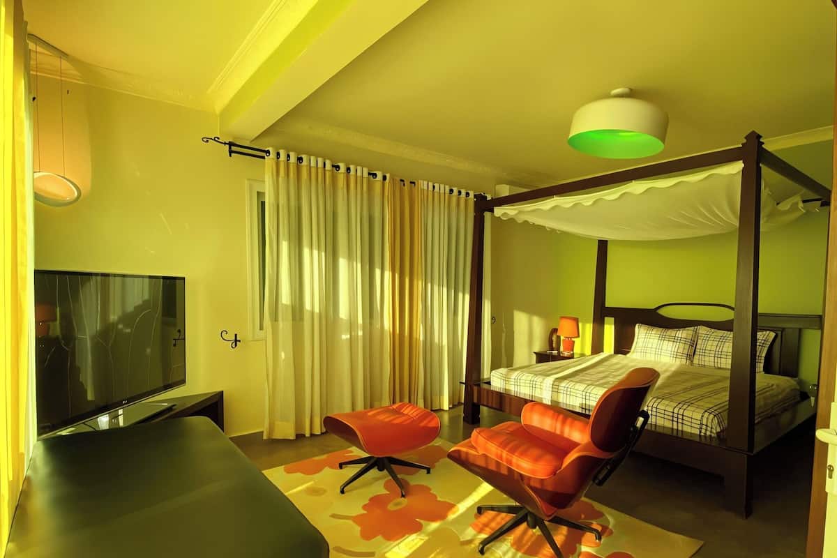A bedroom with a four-poster bed, a TV, a desk, and a chair.