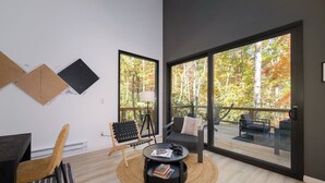 A modern living room with a large window, a round coffee table, a sofa, and a chair.